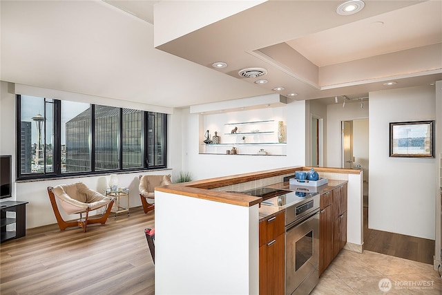 2100 3rd Ave Unit 2503, Seattle, WA 98121 - kitchen with stainless steel range with electric cooktop, modern cabinets, light wood-style flooring, brown cabinets, and recessed lighting