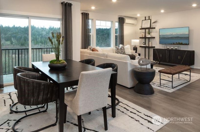 dining room with an AC wall unit, a healthy amount of sunlight, and light hardwood / wood-style floors