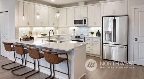 kitchen with a breakfast bar, sink, hanging light fixtures, appliances with stainless steel finishes, and white cabinetry