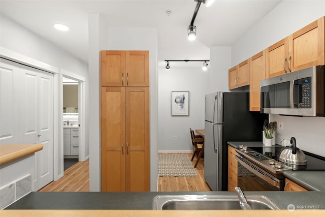 kitchen featuring sink, light hardwood / wood-style floors, track lighting, and appliances with stainless steel finishes