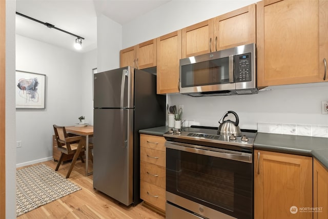 kitchen featuring appliances with stainless steel finishes, light hardwood / wood-style floors, and track lighting