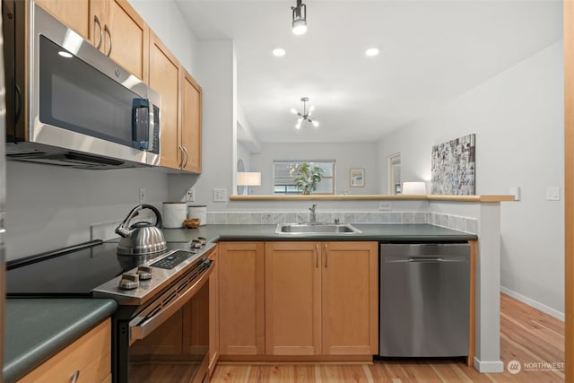 kitchen featuring sink, an inviting chandelier, light wood-type flooring, and appliances with stainless steel finishes