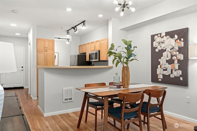 dining room with a chandelier, track lighting, and light hardwood / wood-style flooring