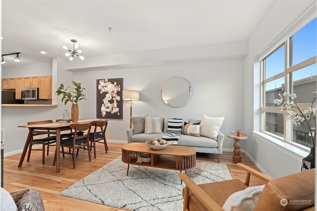 living room featuring a healthy amount of sunlight, a chandelier, and light wood-type flooring