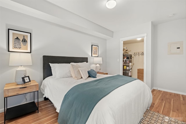 bedroom featuring light wood-type flooring, a walk in closet, electric panel, and a closet