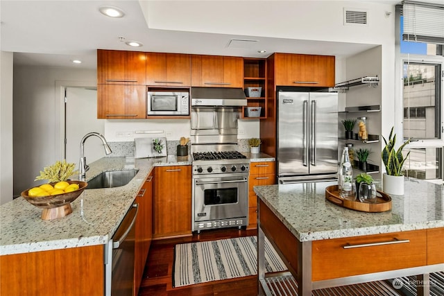 kitchen featuring light stone countertops, a center island, high end appliances, and sink