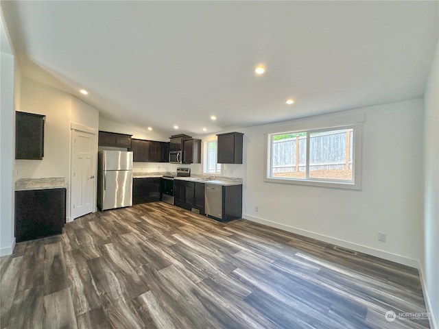 kitchen with dark brown cabinetry, stainless steel appliances, vaulted ceiling, and dark wood-type flooring