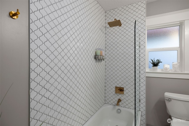 bathroom with tiled shower / bath combo and toilet