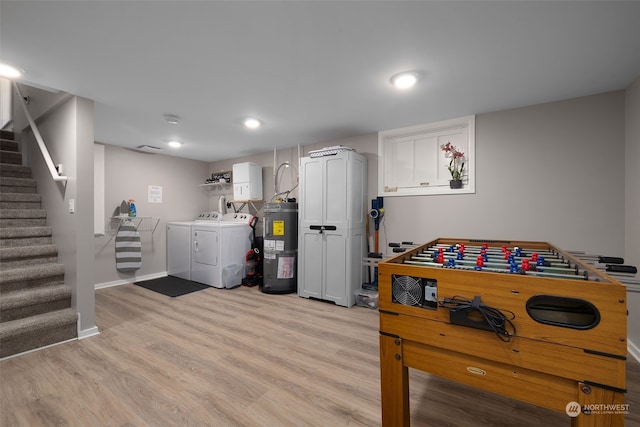 recreation room featuring electric water heater, washer and dryer, and light hardwood / wood-style floors