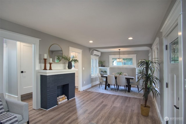 living room with a wall unit AC, hardwood / wood-style floors, and a brick fireplace