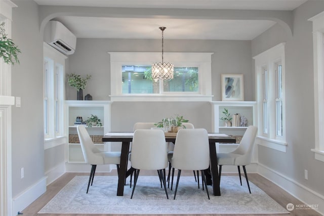 dining area featuring a notable chandelier, light wood-type flooring, and a wall unit AC