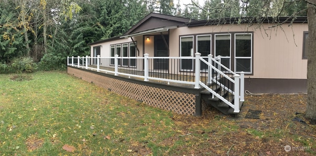 back of house with a deck and a lawn