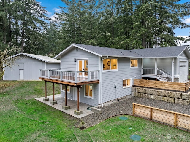 back of property with a lawn, a wooden deck, an outbuilding, and a patio