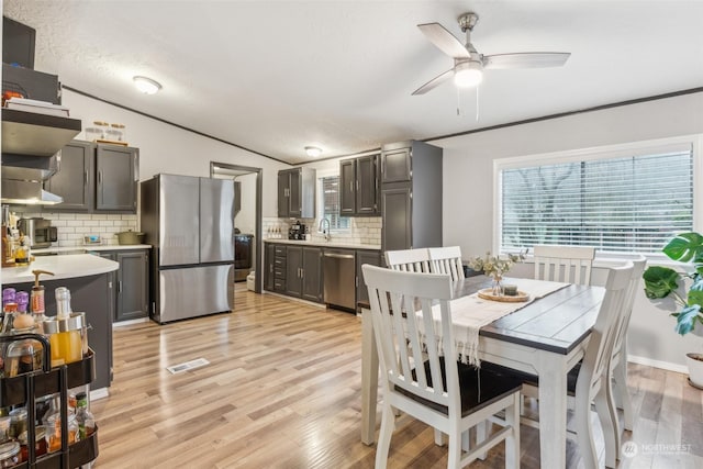 dining area featuring ornamental molding, vaulted ceiling, ceiling fan, sink, and light hardwood / wood-style flooring