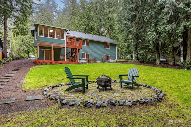 back of property featuring a sunroom, a yard, a fire pit, and a deck