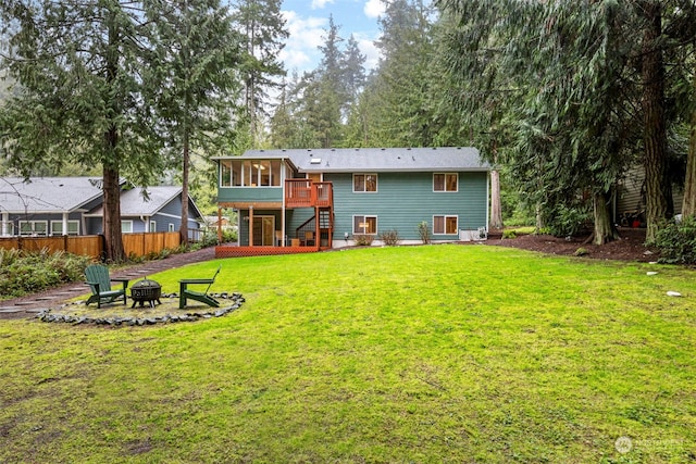 rear view of property featuring a fire pit, a lawn, and a sunroom