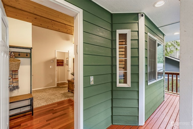 interior space with a textured ceiling, vaulted ceiling, and wood walls