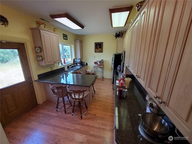 kitchen featuring kitchen peninsula, light brown cabinetry, light hardwood / wood-style floors, and sink