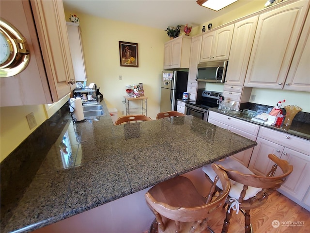 kitchen featuring a kitchen bar, kitchen peninsula, sink, and appliances with stainless steel finishes