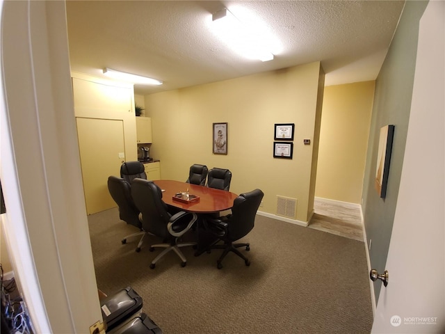 carpeted home office featuring a textured ceiling