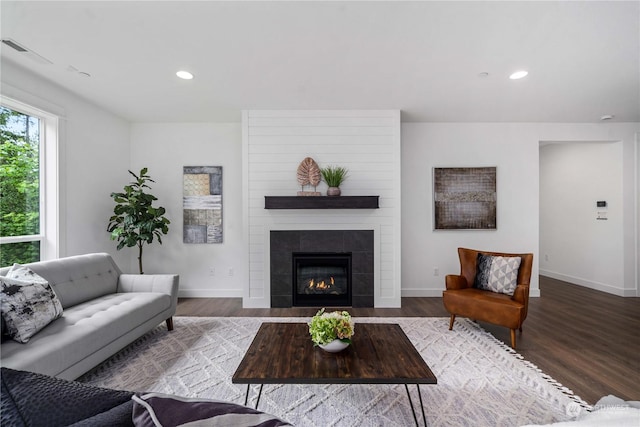 living room with hardwood / wood-style floors and a tiled fireplace