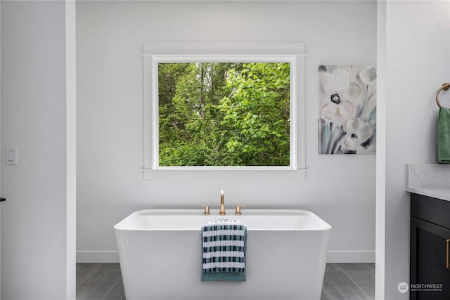 bathroom with tile patterned floors, a washtub, plenty of natural light, and vanity