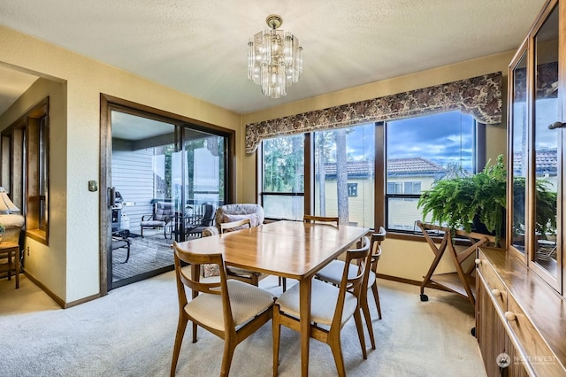 dining area featuring light carpet, a notable chandelier, and a textured ceiling