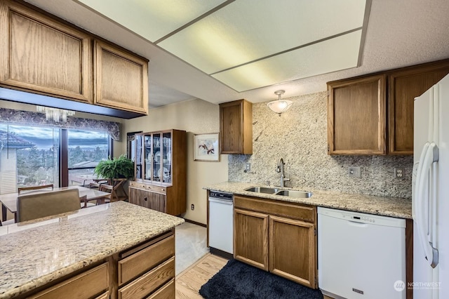 kitchen featuring sink, white appliances, light stone countertops, decorative backsplash, and light wood-type flooring