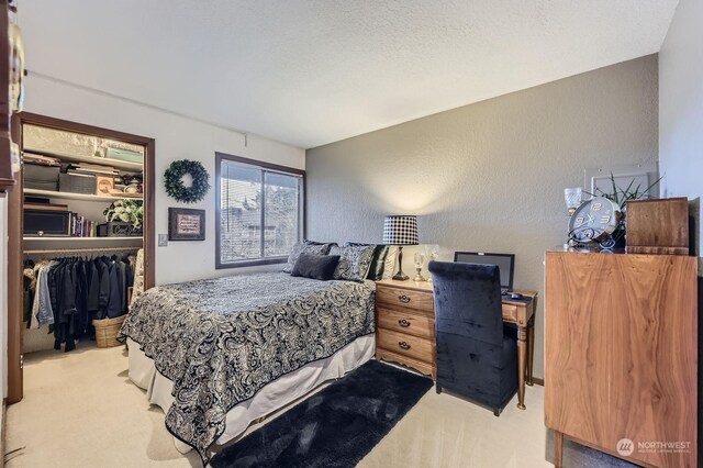 carpeted bedroom with a walk in closet, a closet, and a textured ceiling