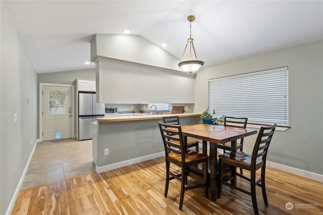 dining room featuring light hardwood / wood-style floors, lofted ceiling, and sink