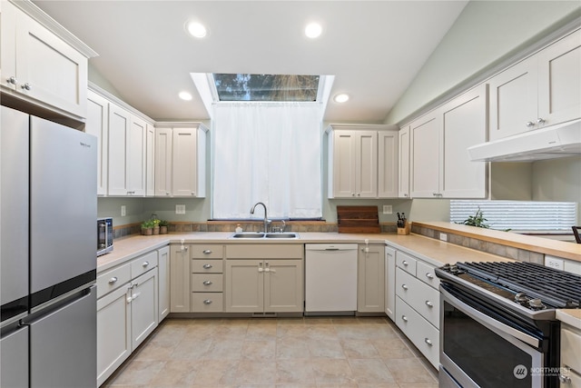 kitchen with lofted ceiling, sink, white cabinetry, and stainless steel appliances