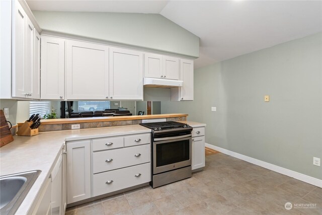 kitchen with lofted ceiling, backsplash, sink, stainless steel stove, and white cabinetry