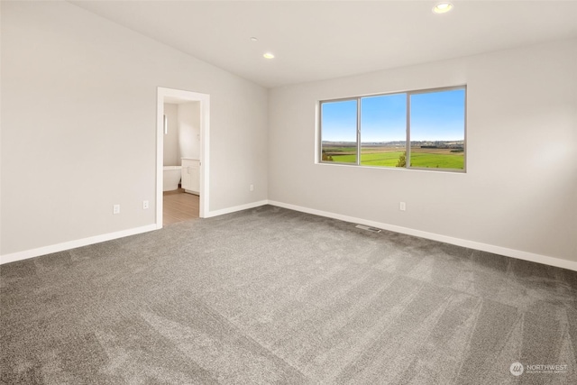 unfurnished bedroom with carpet, ensuite bathroom, and vaulted ceiling