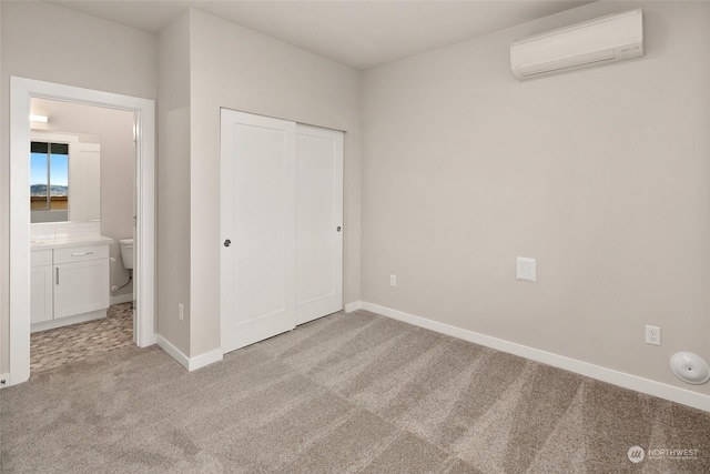 unfurnished bedroom with light colored carpet, an AC wall unit, connected bathroom, and a closet