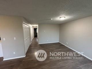 unfurnished room featuring a textured ceiling and dark wood-type flooring