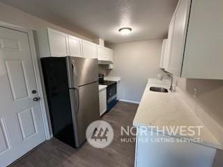 kitchen featuring a textured ceiling, sink, electric range, white cabinetry, and stainless steel refrigerator