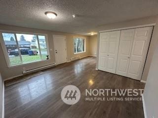 interior space featuring dark hardwood / wood-style flooring, baseboard heating, and a textured ceiling