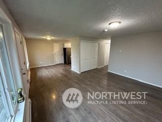 spare room featuring dark hardwood / wood-style flooring and a textured ceiling