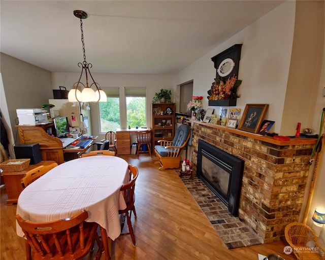 dining space with hardwood / wood-style floors and a brick fireplace