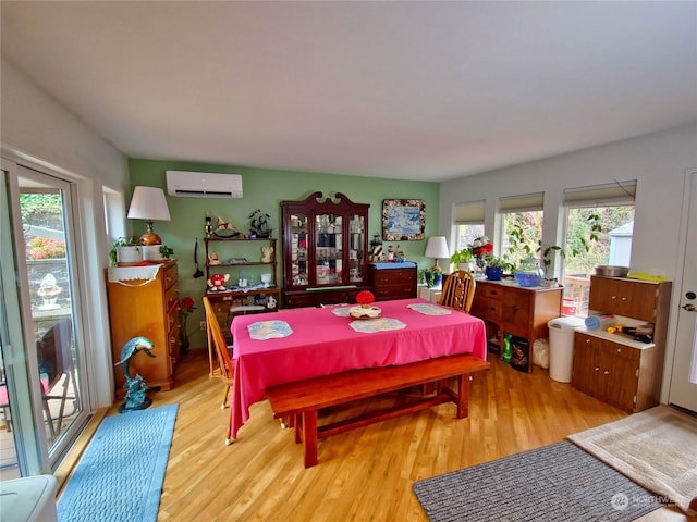 dining area featuring light wood-type flooring and an AC wall unit