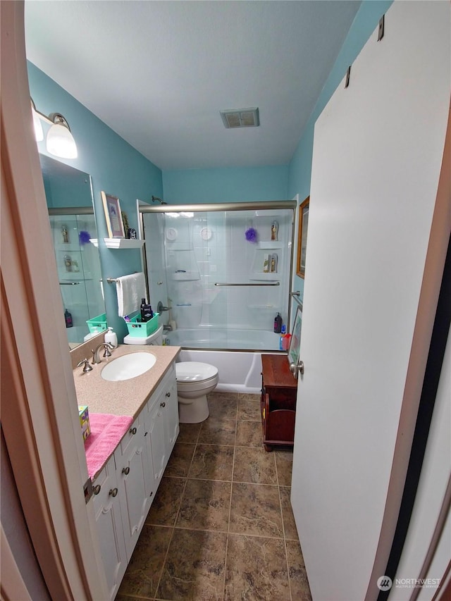 full bathroom featuring vanity, enclosed tub / shower combo, and toilet