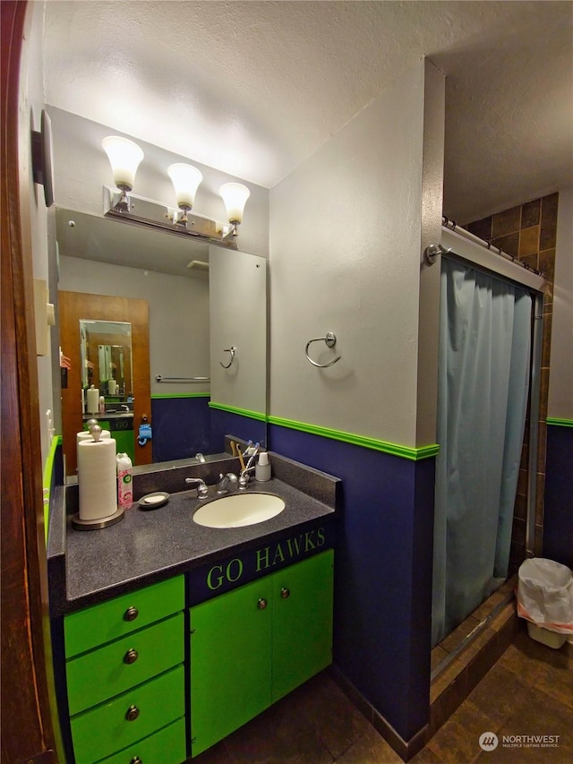 bathroom featuring vanity, a textured ceiling, and tiled shower