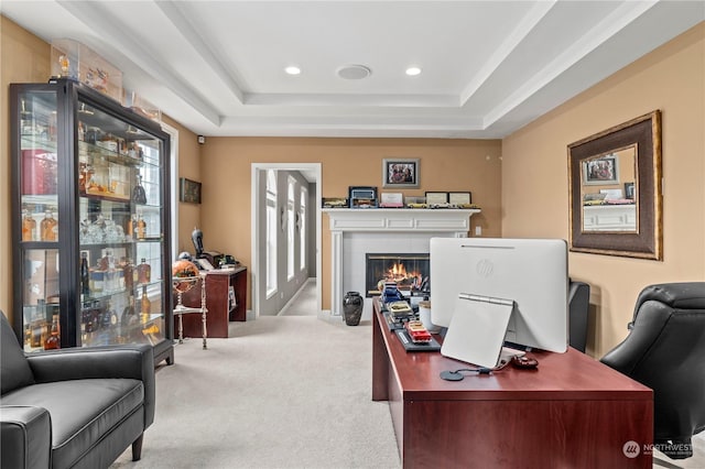 carpeted home office with a raised ceiling and a healthy amount of sunlight