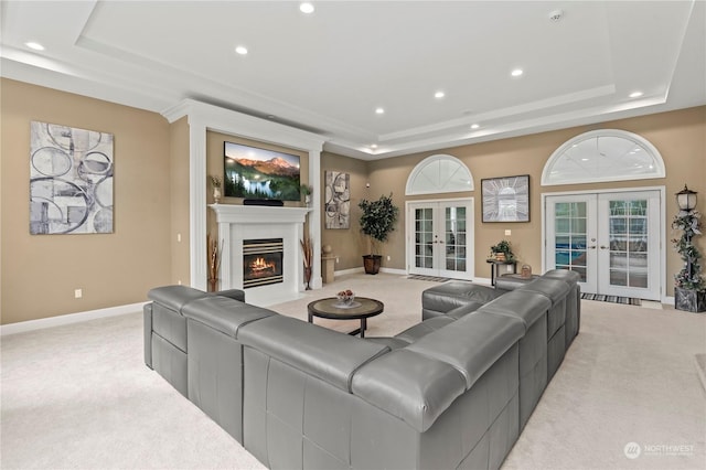 carpeted living room featuring a tray ceiling and french doors