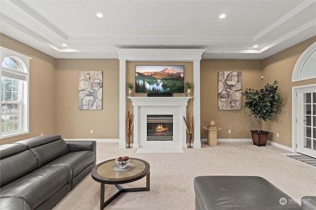 living room featuring a raised ceiling, light colored carpet, and a tile fireplace