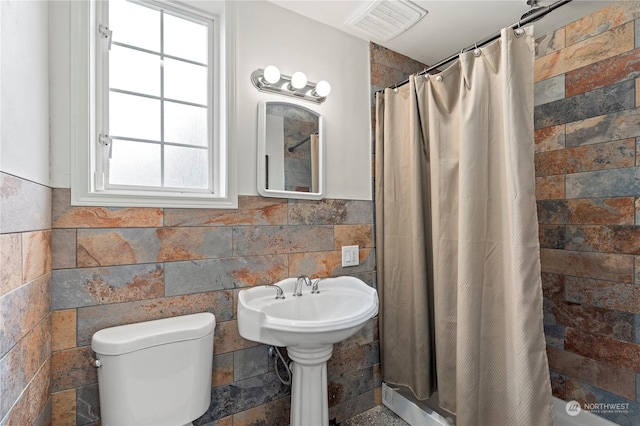 bathroom with a wealth of natural light, toilet, and walk in shower