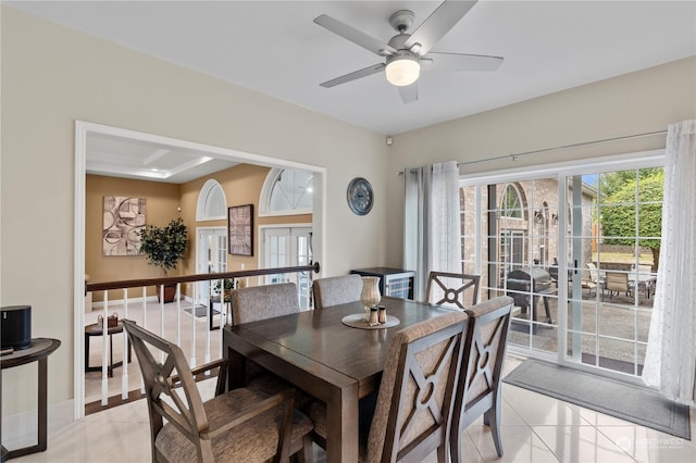 tiled dining room featuring ceiling fan and french doors