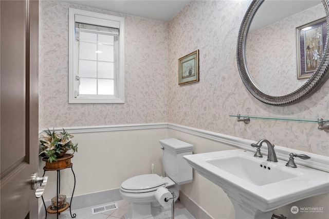 bathroom with toilet, tile patterned floors, and sink