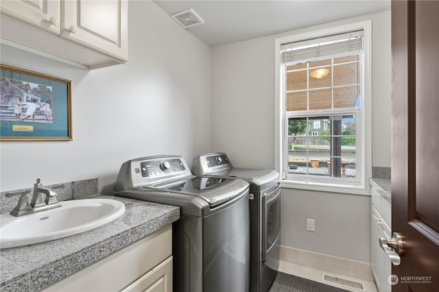 laundry area featuring cabinets, washing machine and dryer, sink, and tile patterned floors