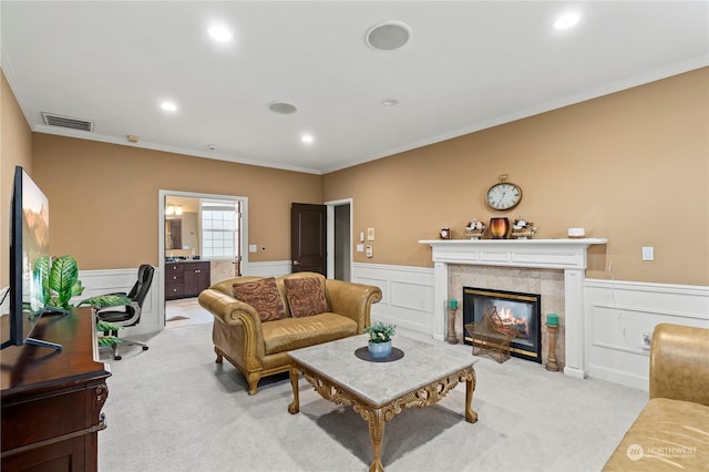 living room featuring a tile fireplace, light colored carpet, and crown molding